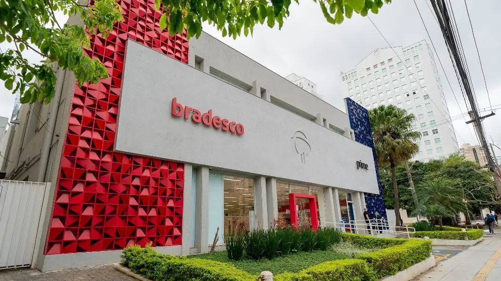 Fachada do Bradesco com gráfico de lucro em alta, representando a recuperação financeira e os resultados positivos do banco em 2025.