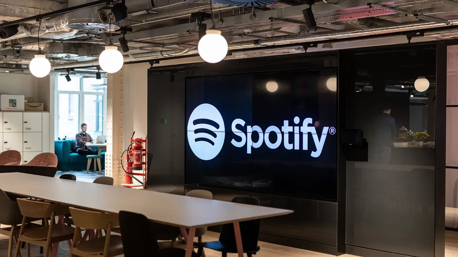 Sede do Spotify com telas digitais mostrando interface do app e crescimento global de usuários